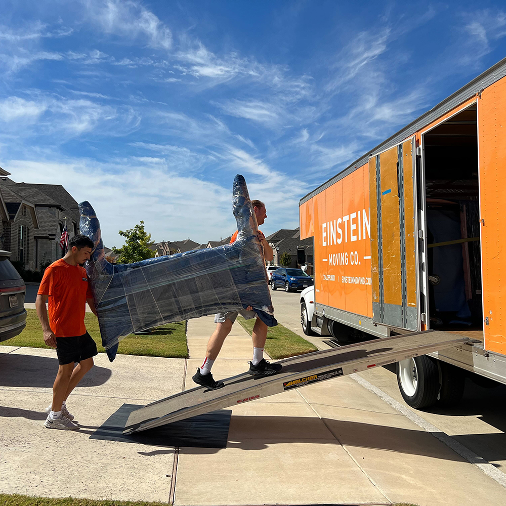 Two men carrying a piece of furniture into moving truck.