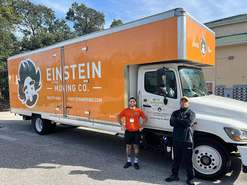 Two movers from Tampa posing for a photo in front of their moving truck.