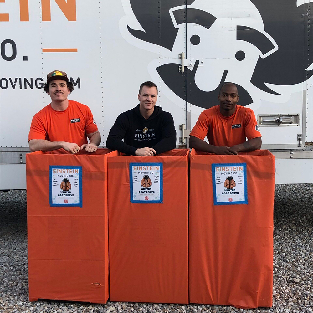 3 movers outside of the moving truck with donation boxes.