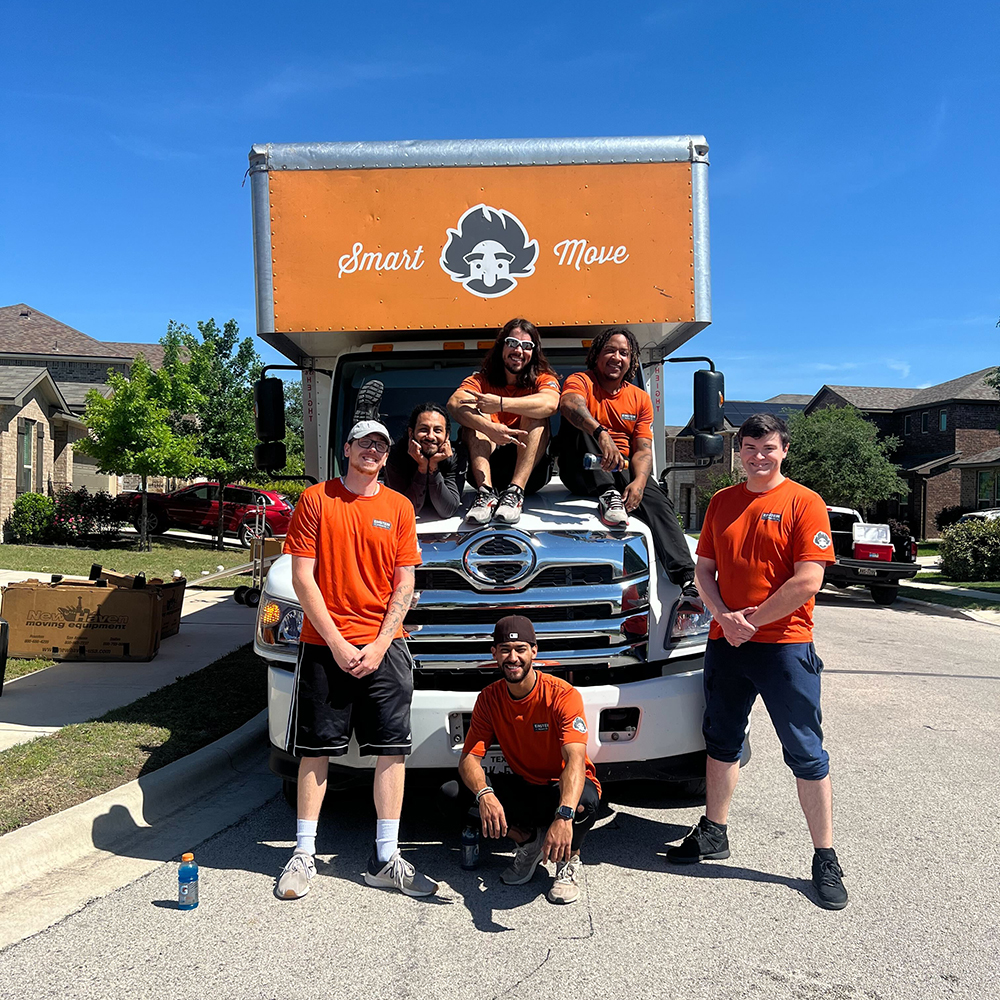 Team of professional movers posing in front of their moving truck in a neighborhood in Round Rock, TX.